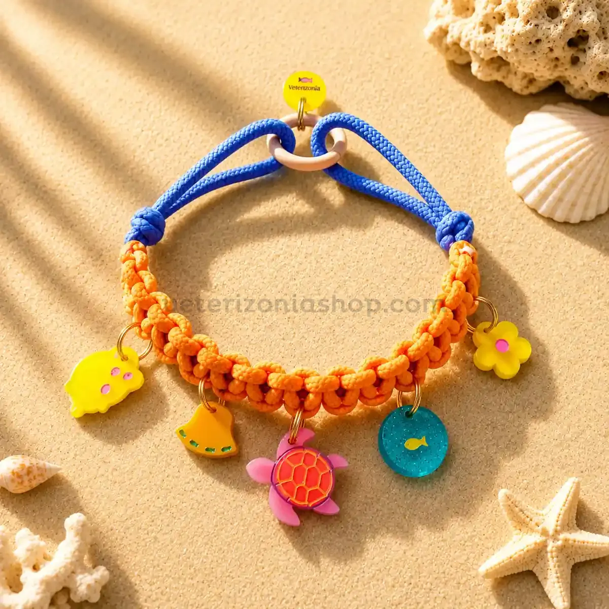 Collar con charms decorativos para perros pequeños modelo Océano con cordón naranja y azul, charms marinos y fondo arena estilo playa.